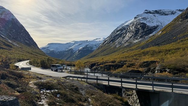 Breathtaking landscape of a road through snow-capped mountains and a river in Norway.