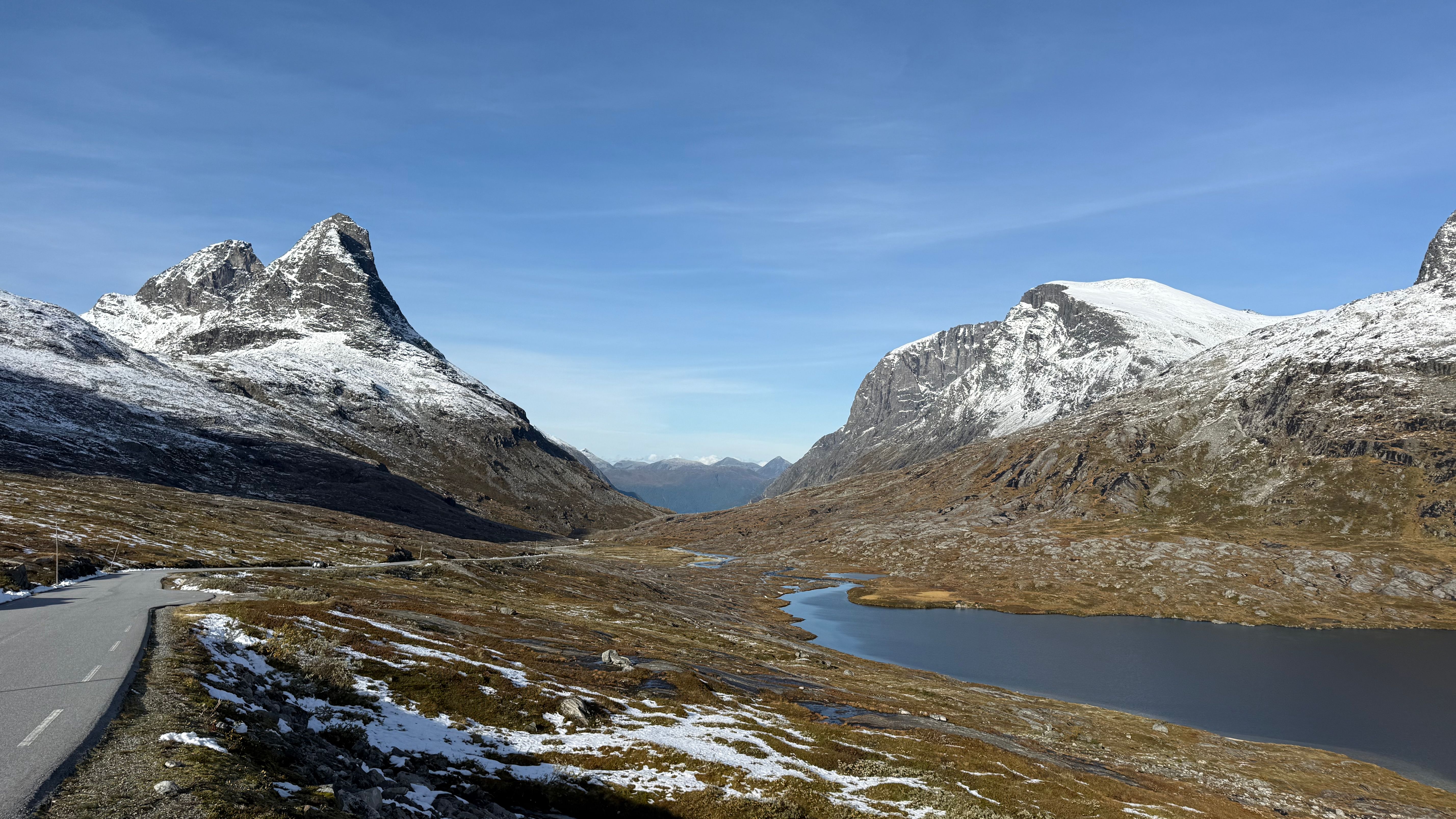 A picturesque view of Norwegian mountains with a winding road under a clear blue sky.