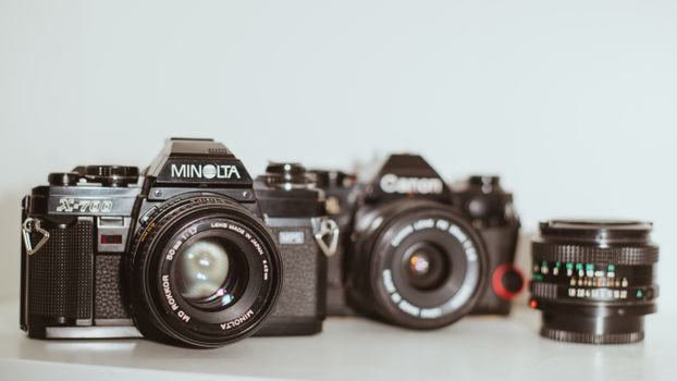 Classic Minolta and Canon analog cameras with a vintage lens on white background.