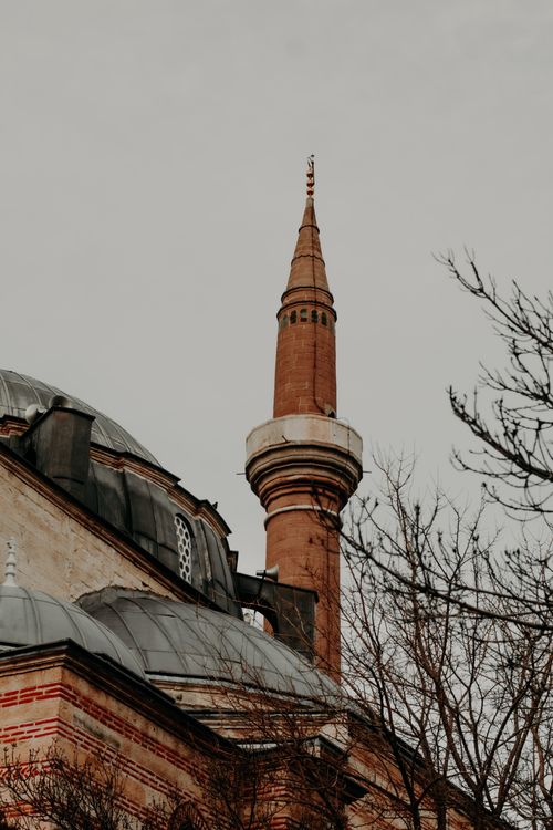 Free A picturesque view of a historical mosque minaret surrounded by trees in Konya, Türkiye. Stock Photo
