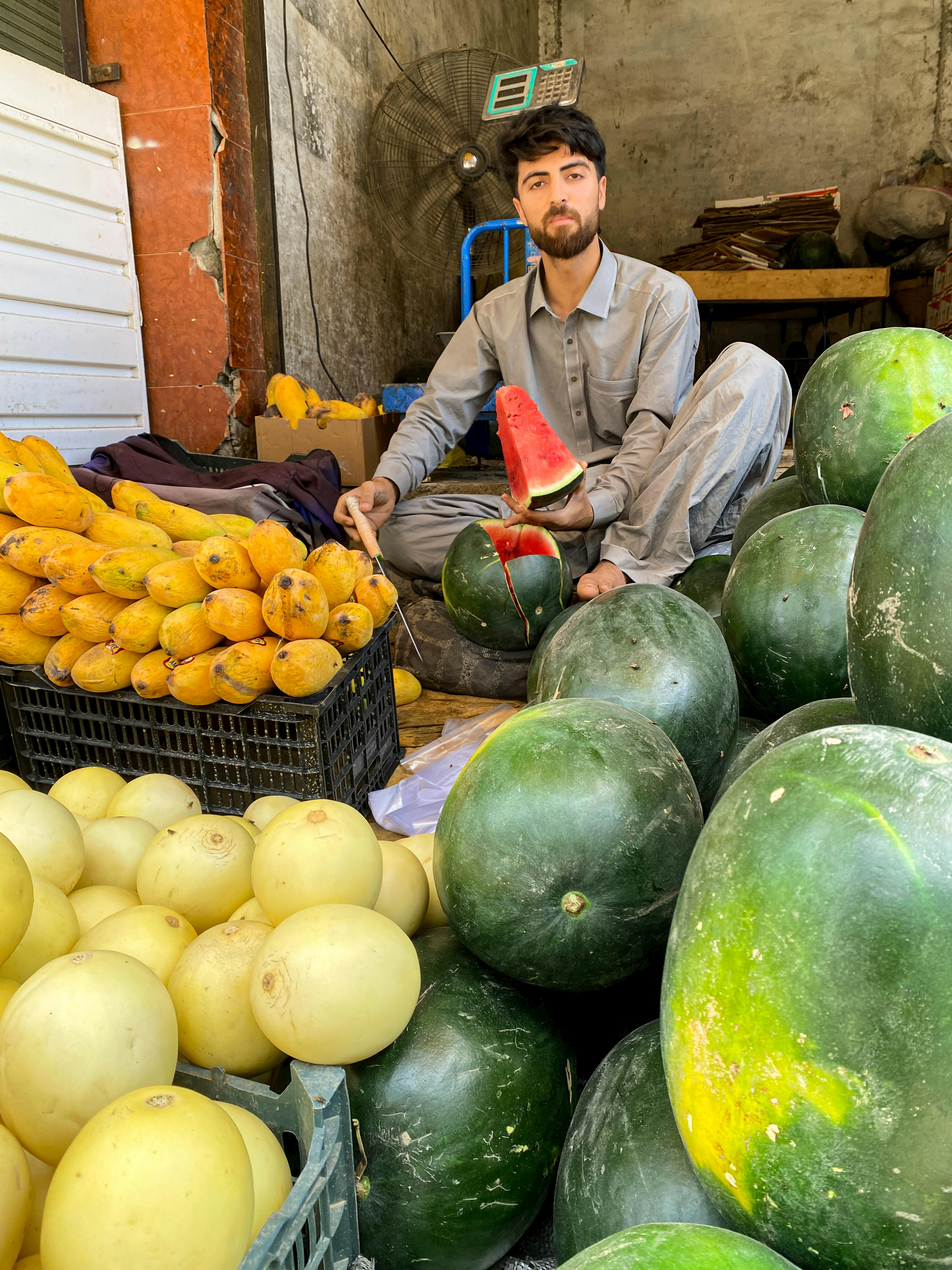 A street vendor selling fresh watermelons and fruits in Mingora, Pakistan bazaar.