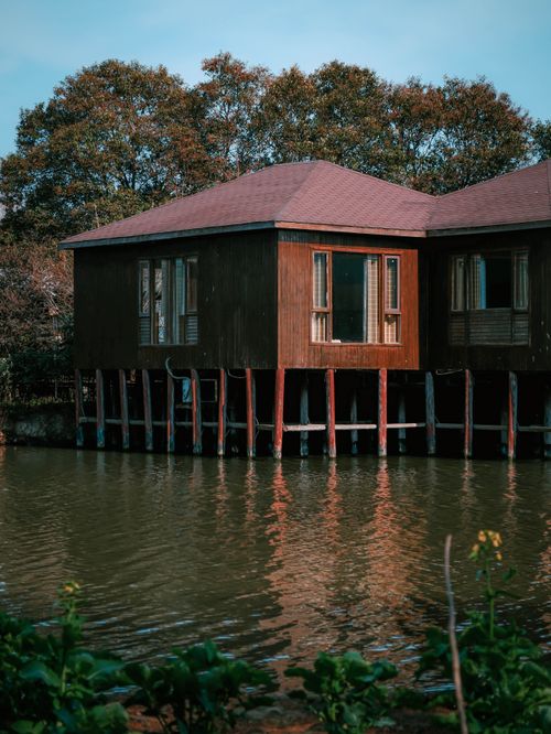 Free Tranquil wooden cabin on stilts by a lake, surrounded by autumn trees. Stock Photo