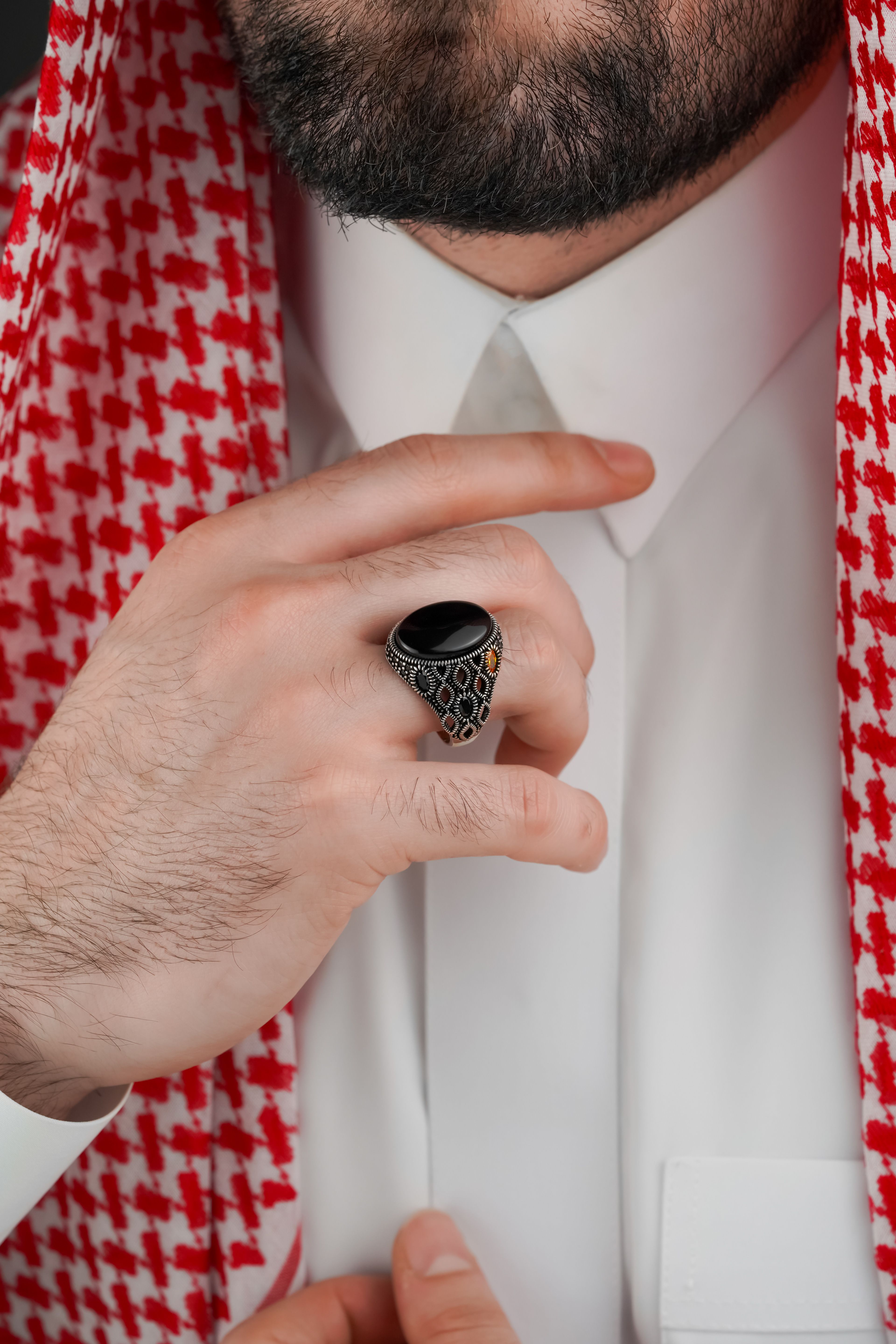 Close-up of a hand wearing an ornate black onyx ring on traditional Middle Eastern attire.