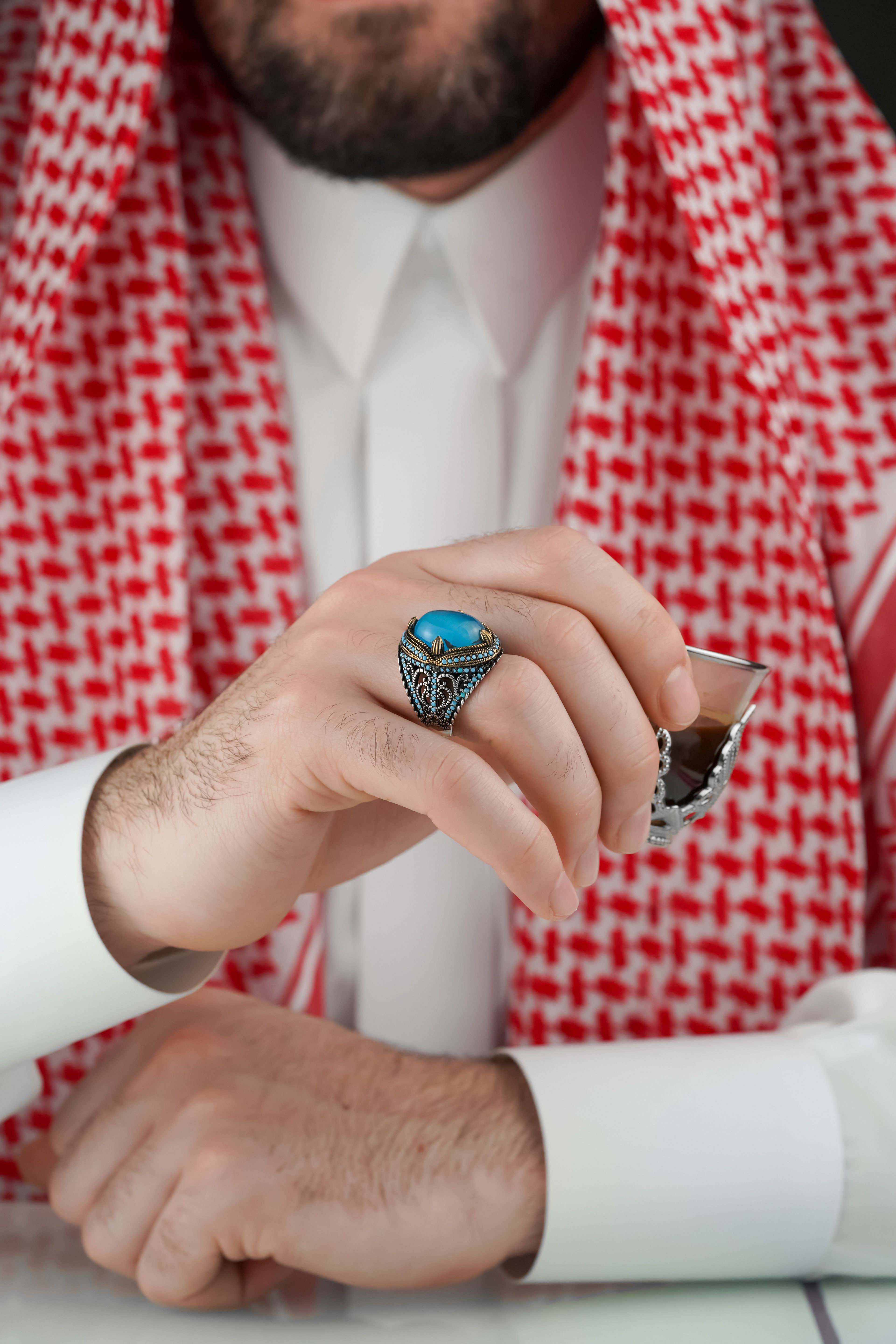 A detailed shot of a traditional Middle Eastern ring worn with cultural attire, exuding elegance and style.