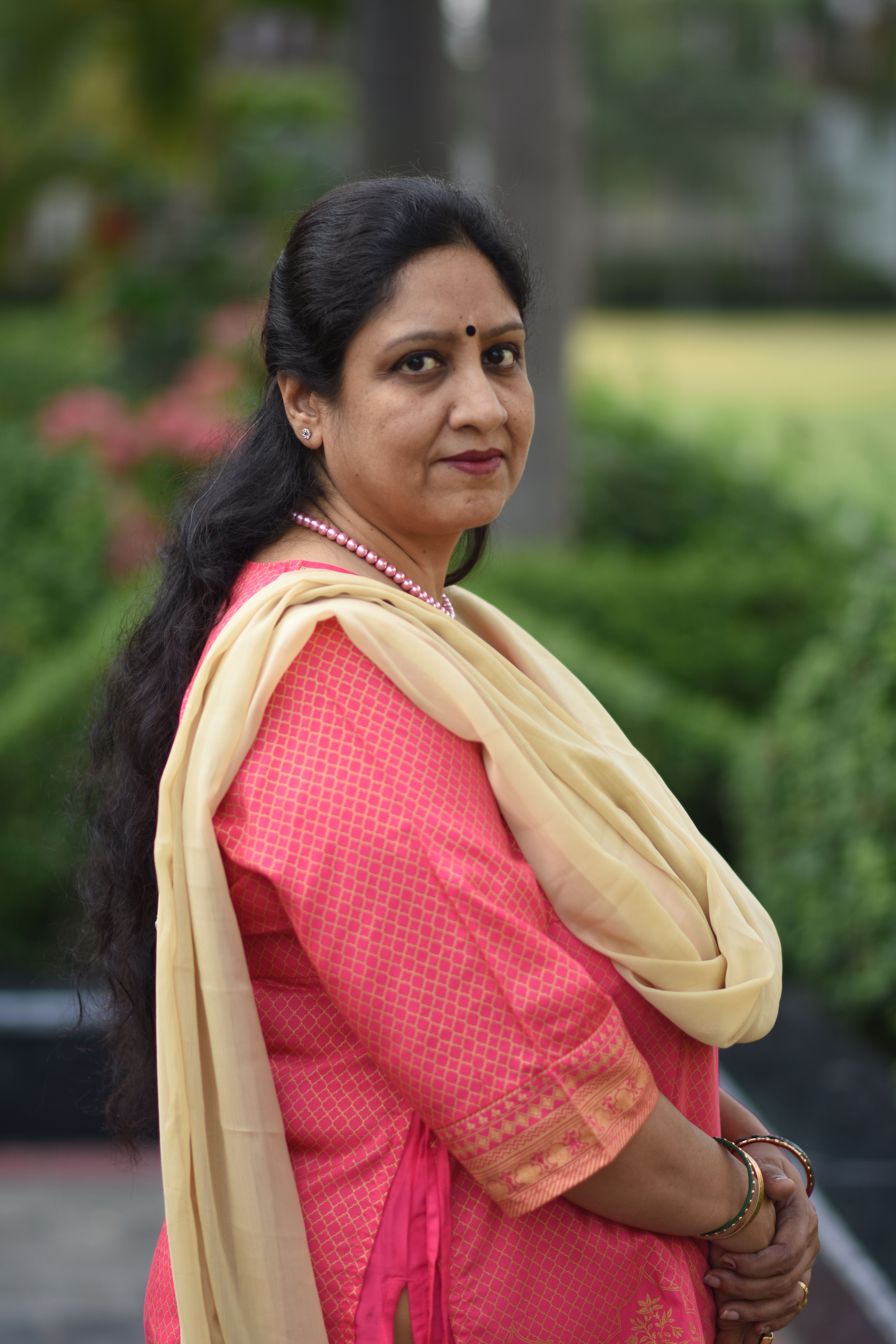 A woman in traditional Indian attire stands outdoors, exuding elegance and poise.