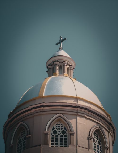 Free A beautifully detailed church dome with a cross against a clear blue sky, showcasing architectural elegance. Stock Photo