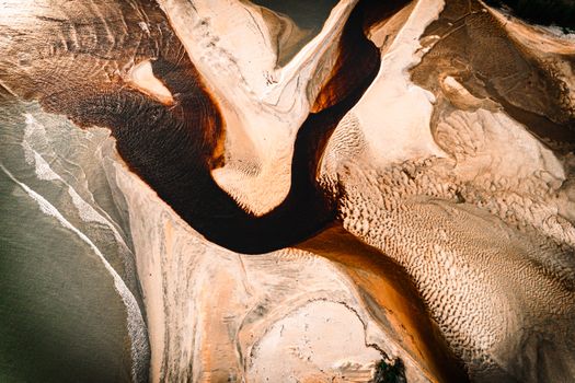 A stunning aerial view showcasing intricate sand patterns and a winding river through a desert landscape.