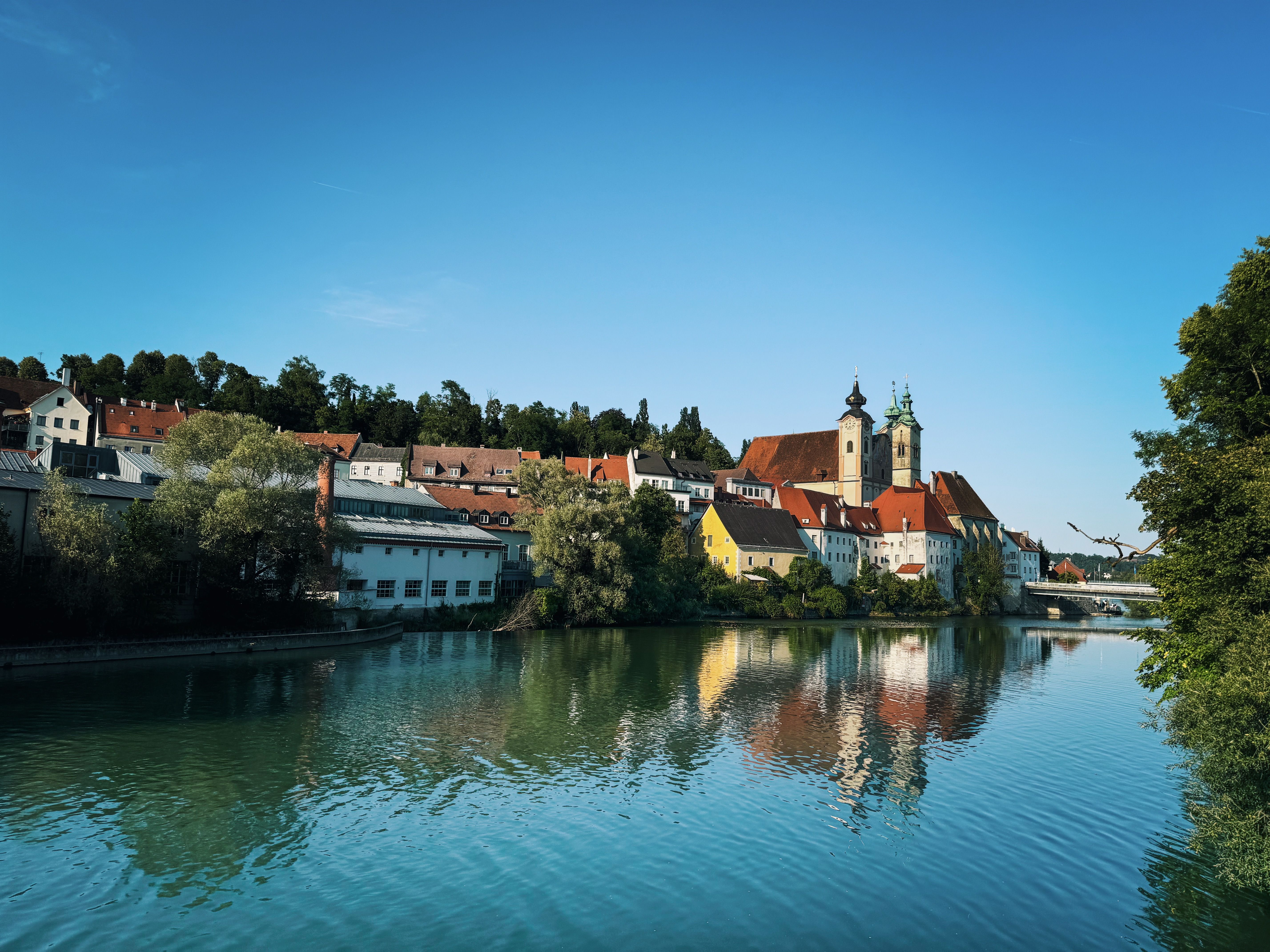 Beautiful daytime view of Steyr, Austria along the river with stunning reflections of historic buildings.