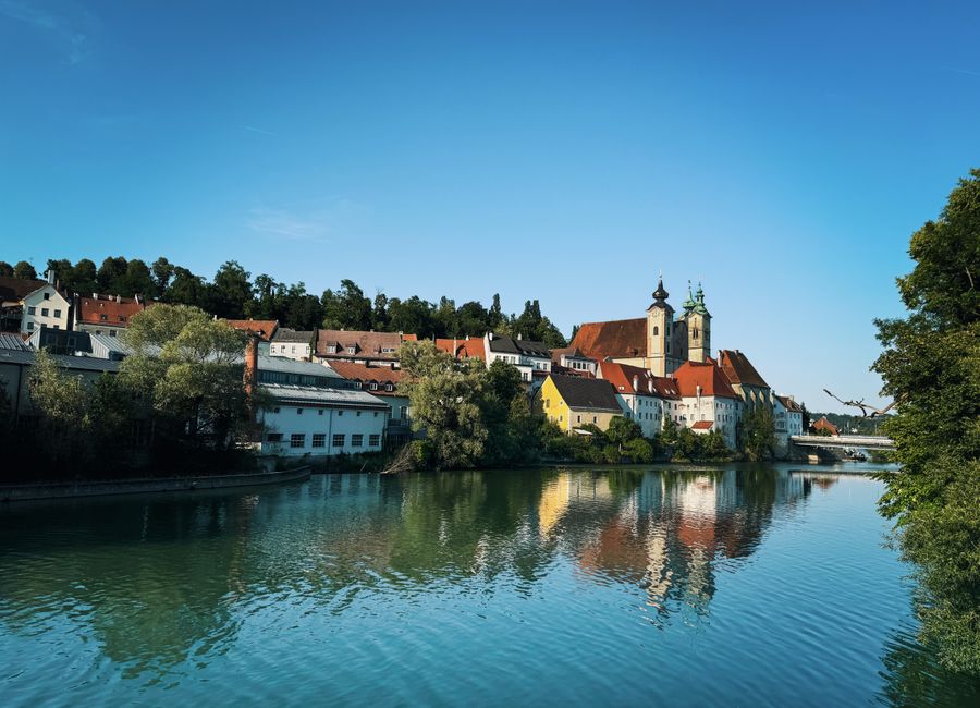 Beautiful daytime view of Steyr, Austria along the river with stunning reflections of historic buildings.