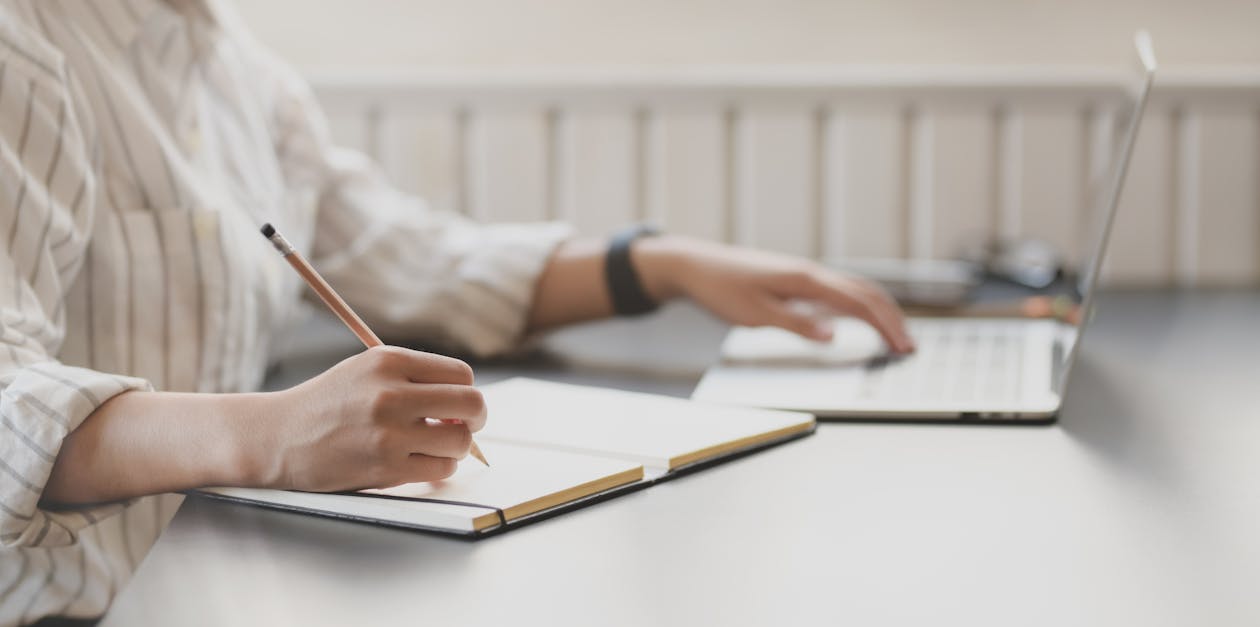 Photo Of Person Writing On Notebook