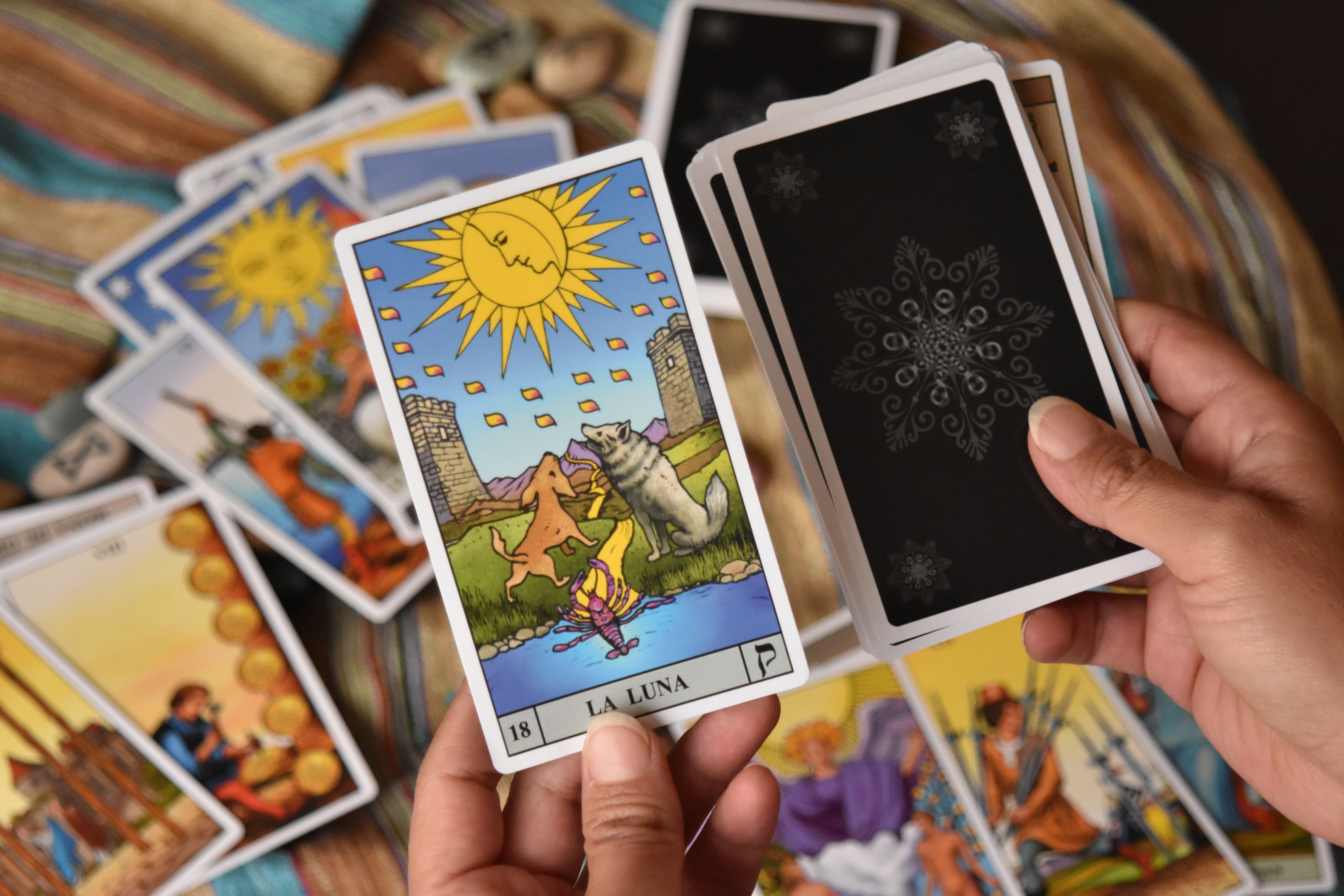 [ColoSach]-detailed-view-of-hands-holding-tarot-cards,-featuring-vibrant-artwork-with-mystical-themes.