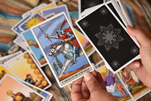 Close-up of hands with tarot cards focused on Knight of Swords.