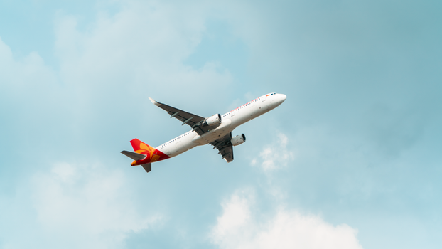 A commercial airplane flying high in a clear, bright blue sky.