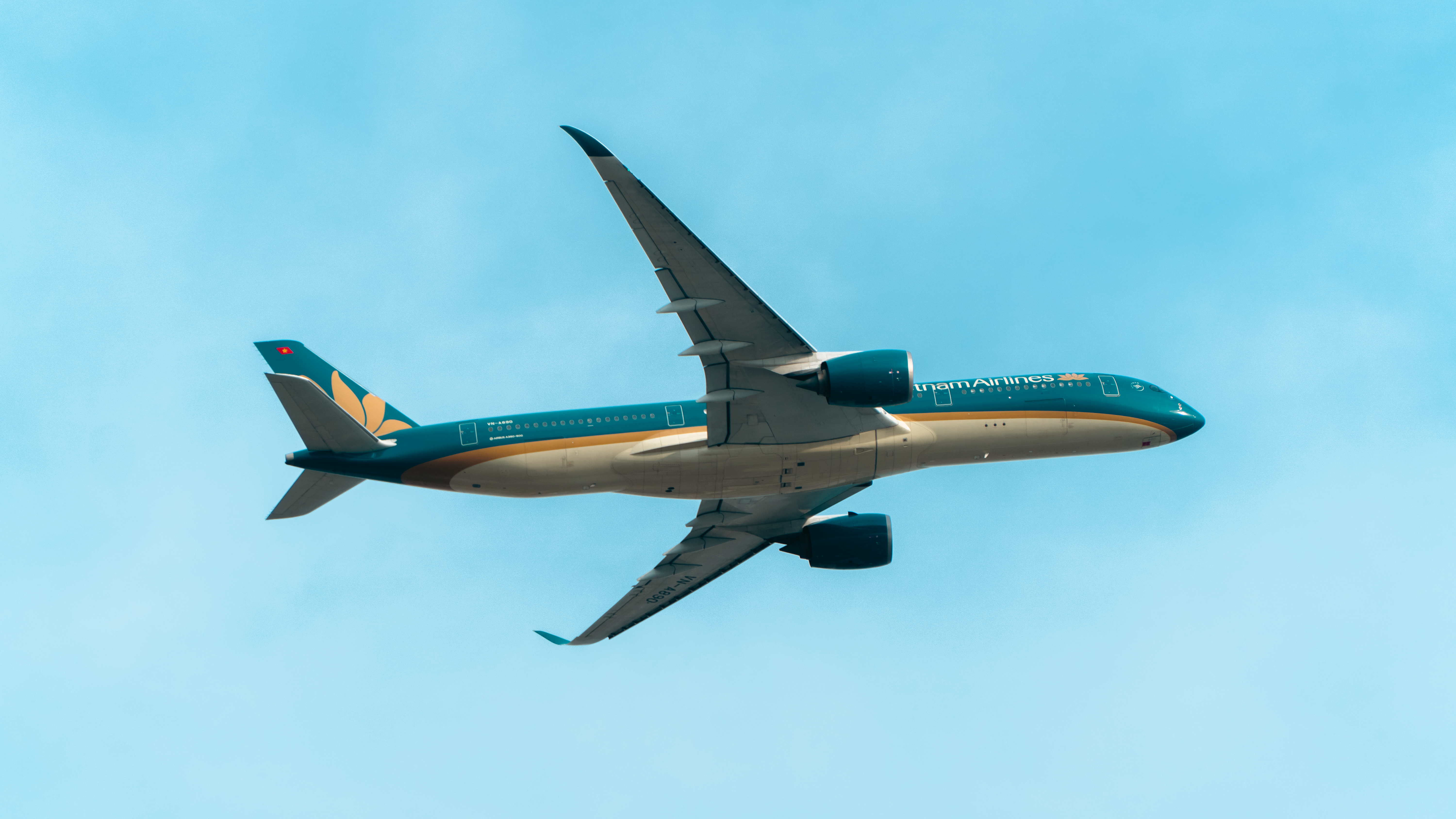 A modern passenger airplane flying high against clear blue sky.