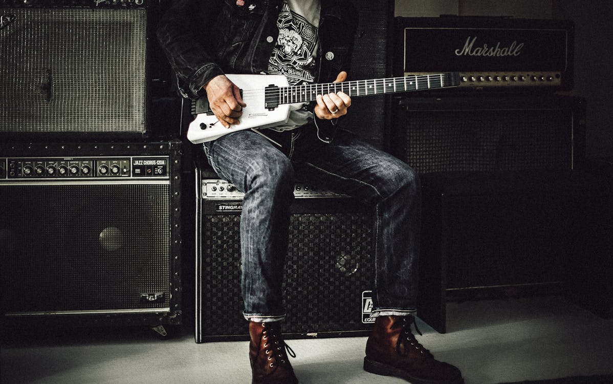 エレクトリックギターを弾くギターアンプに座っている男 無料の写真素材