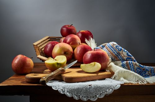 Free A captivating still life arrangement featuring fresh apples, a knife, and a rustic cloth on a wooden table. Stock Photo