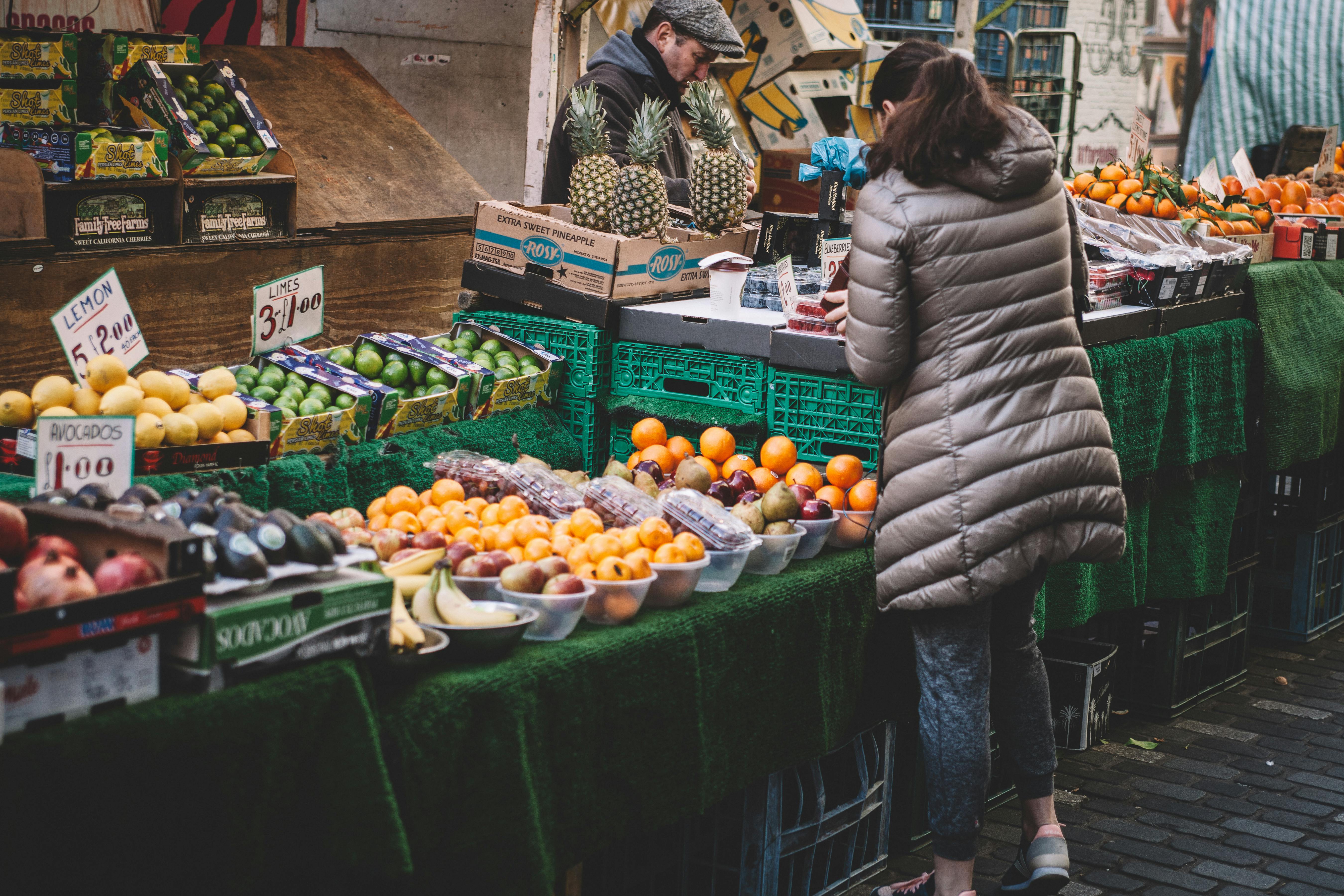 woman standing in front of assorted fruits displayed