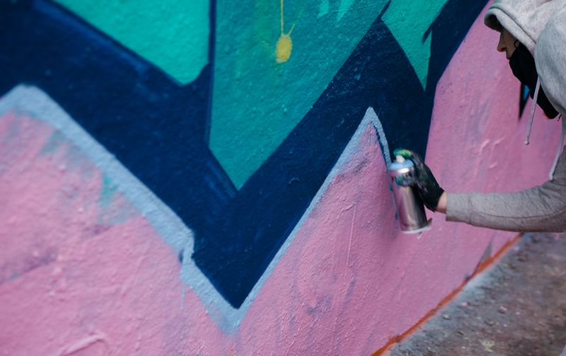 Artist spray painting a colourful graffiti mural