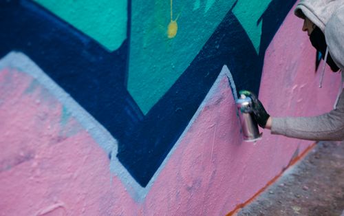 Free A street artist spray painting a colorful abstract mural on a concrete wall outdoors. Stock Photo