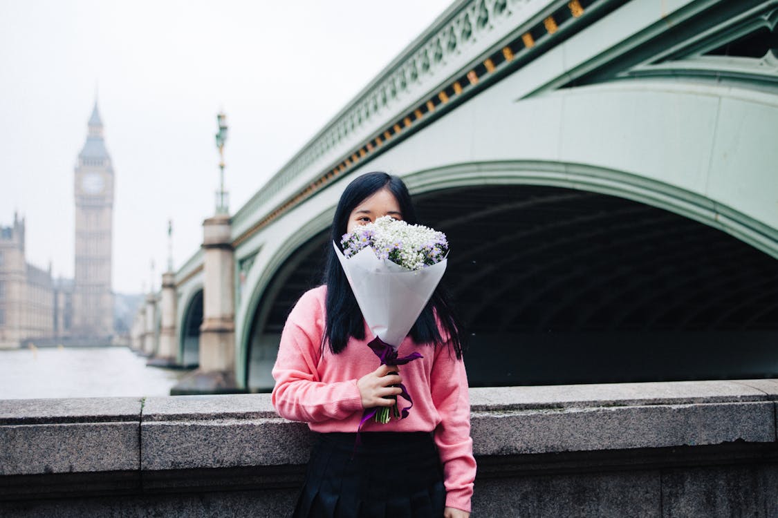무료 꽃다발을 들고 다리에 서있는 여자 스톡 사진
