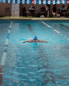 An athlete swimming in a pool under clear skies in San Miguel de Allende.
