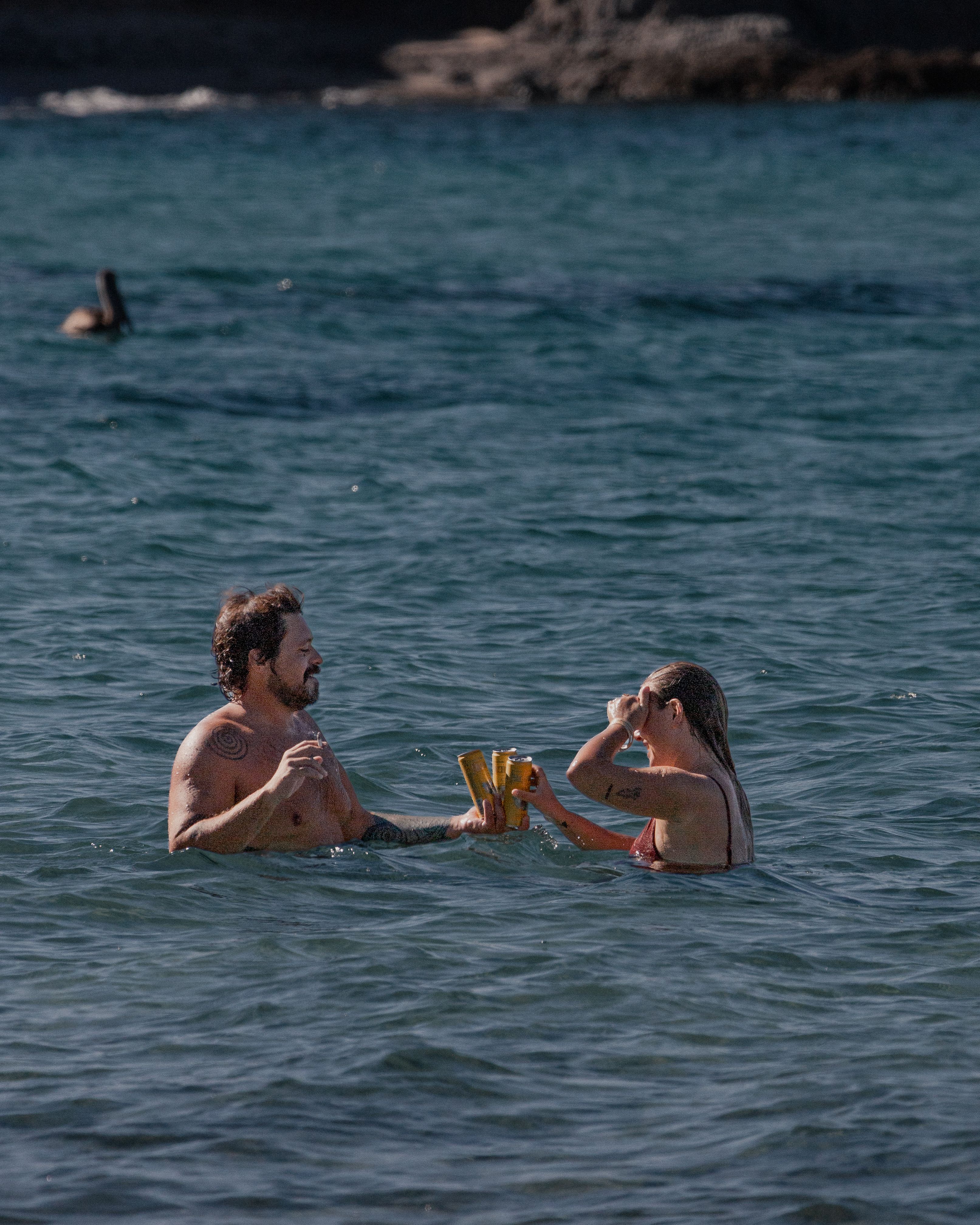 Free A couple enjoys drinks while swimming in the ocean at Cabo San Lucas beach. Stock Photo
