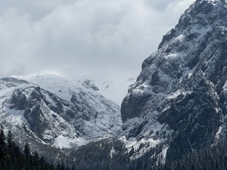 Breathtaking view of the snow-covered Tatra Mountains with dramatic clouds above, capturing the essence of winter.