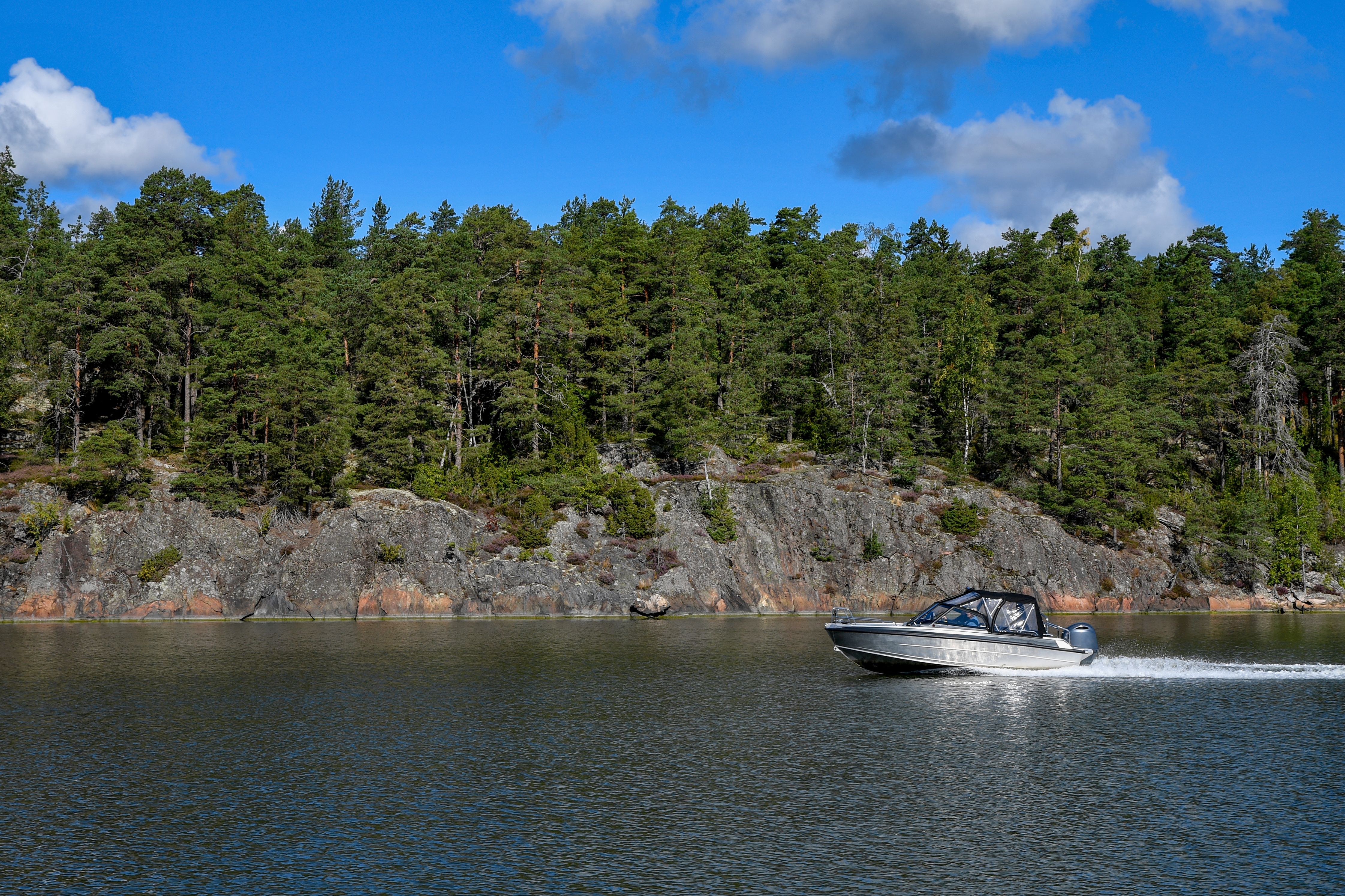 Gratis In una giornata di sole, un motoscafo sfreccia lungo la costa rocciosa di Turku, in Finlandia. Foto a disposizione