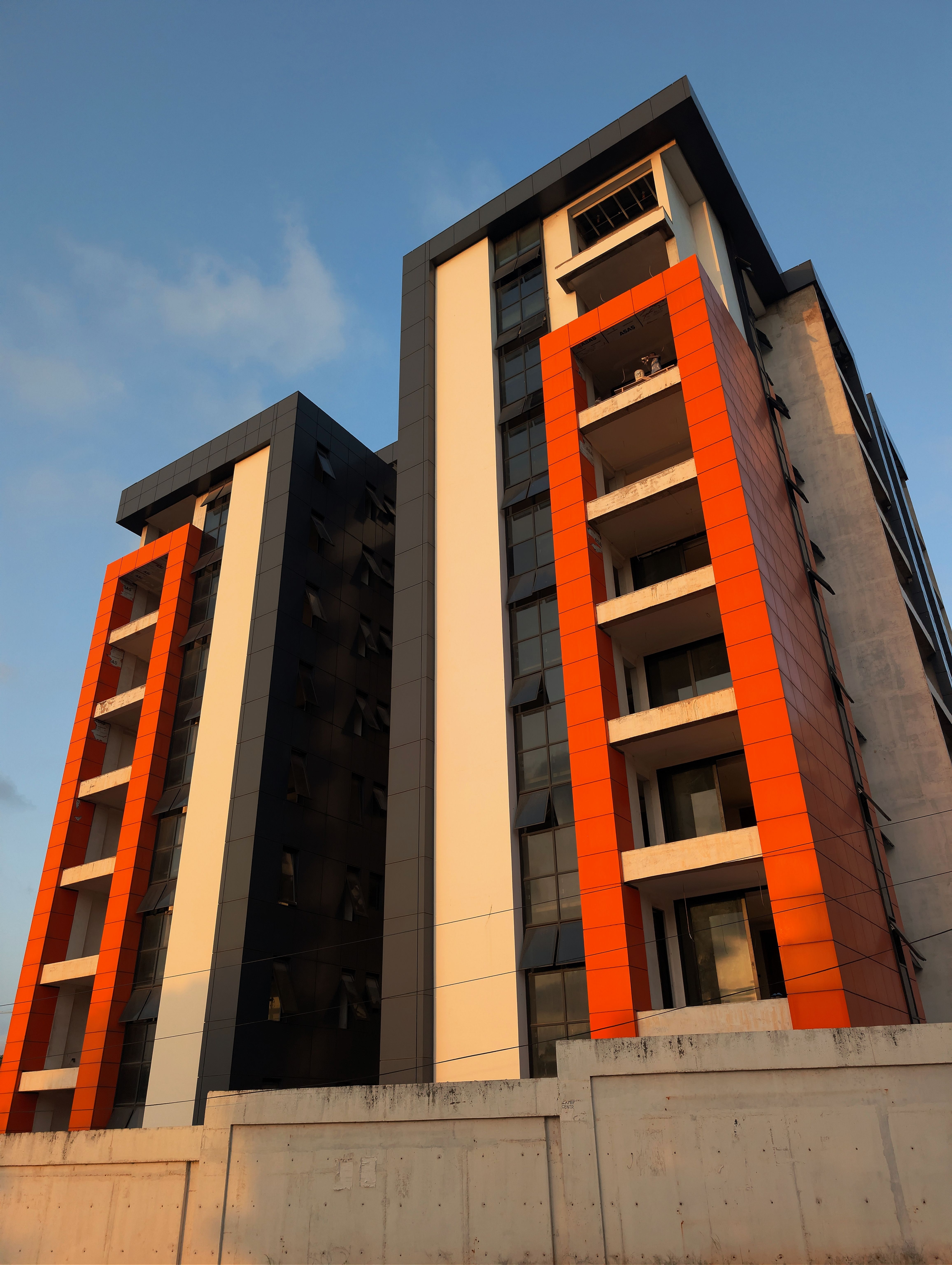 Contemporary architectural design of a residential building with an orange facade lit by sunset.