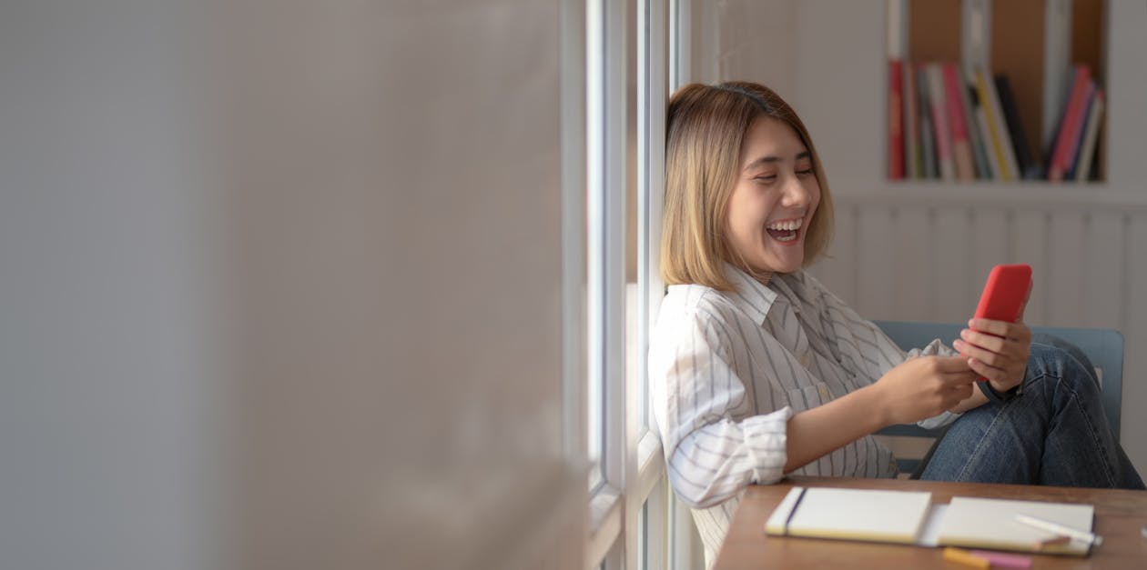 A Joyous Woman Using A Smartphone and laughing