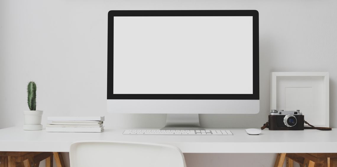 Professional reviewing a clean organized office workstation with computer and desk accessories