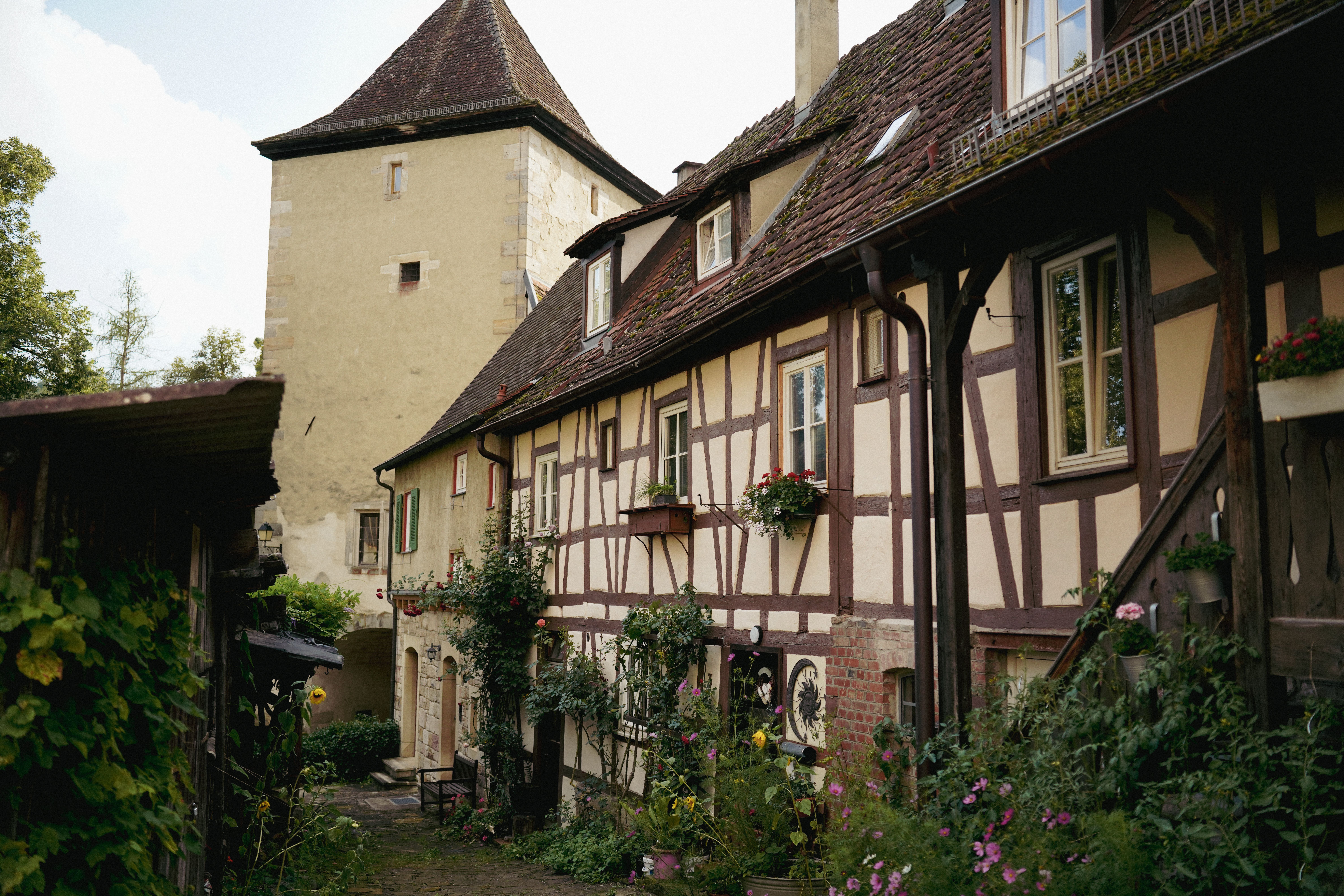 Explorez une charmante maison à colombages entourée d'une végétation luxuriante, un exemple typique de l'architecture européenne traditionnelle.