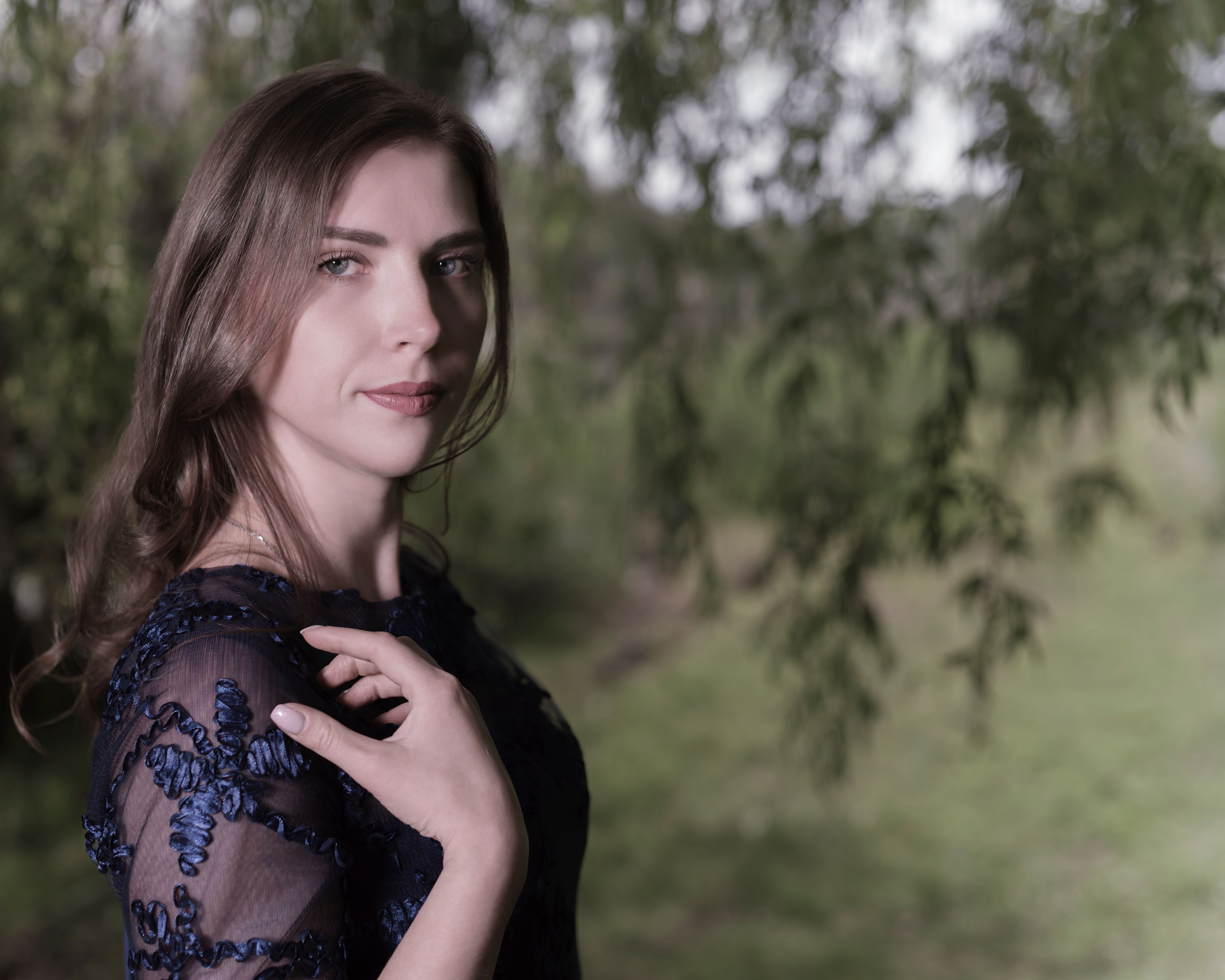 A beautiful woman in a blue dress poses elegantly outdoors in Lyon.