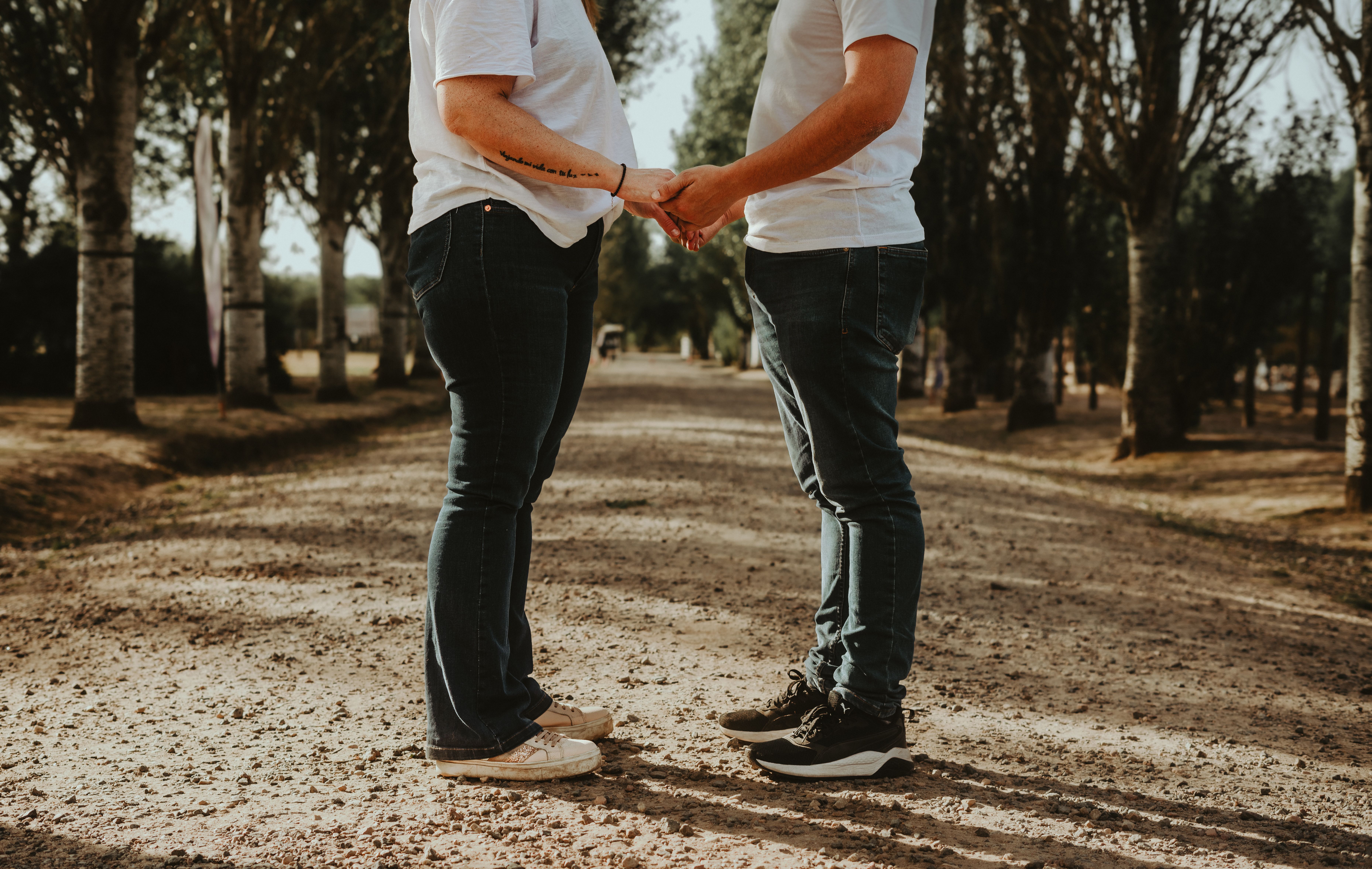 A couple holding hands on a tree-lined path, symbolizing love and connection.