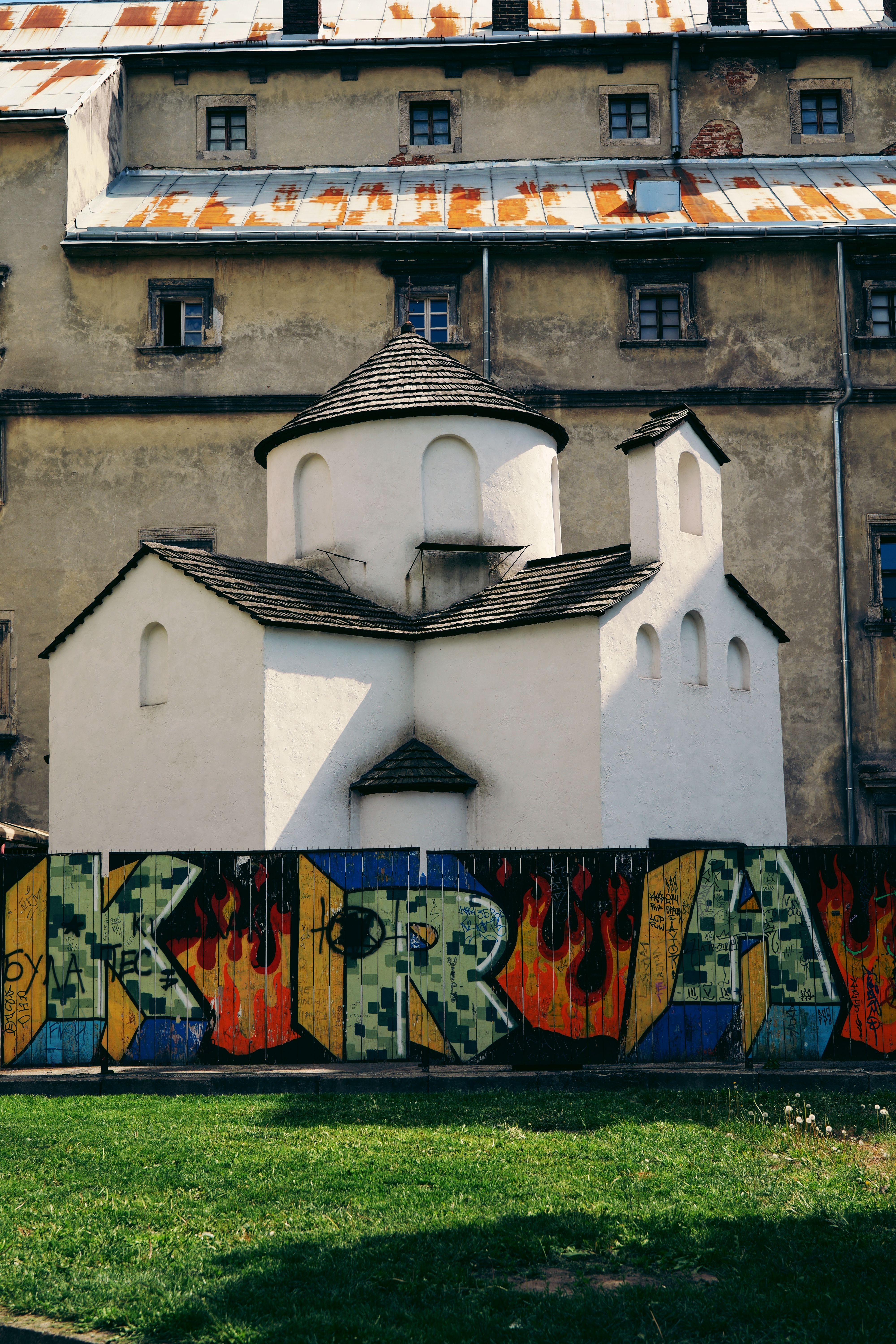 Quaint chapel facade against an urban graffiti backdrop in Lviv, Ukraine.