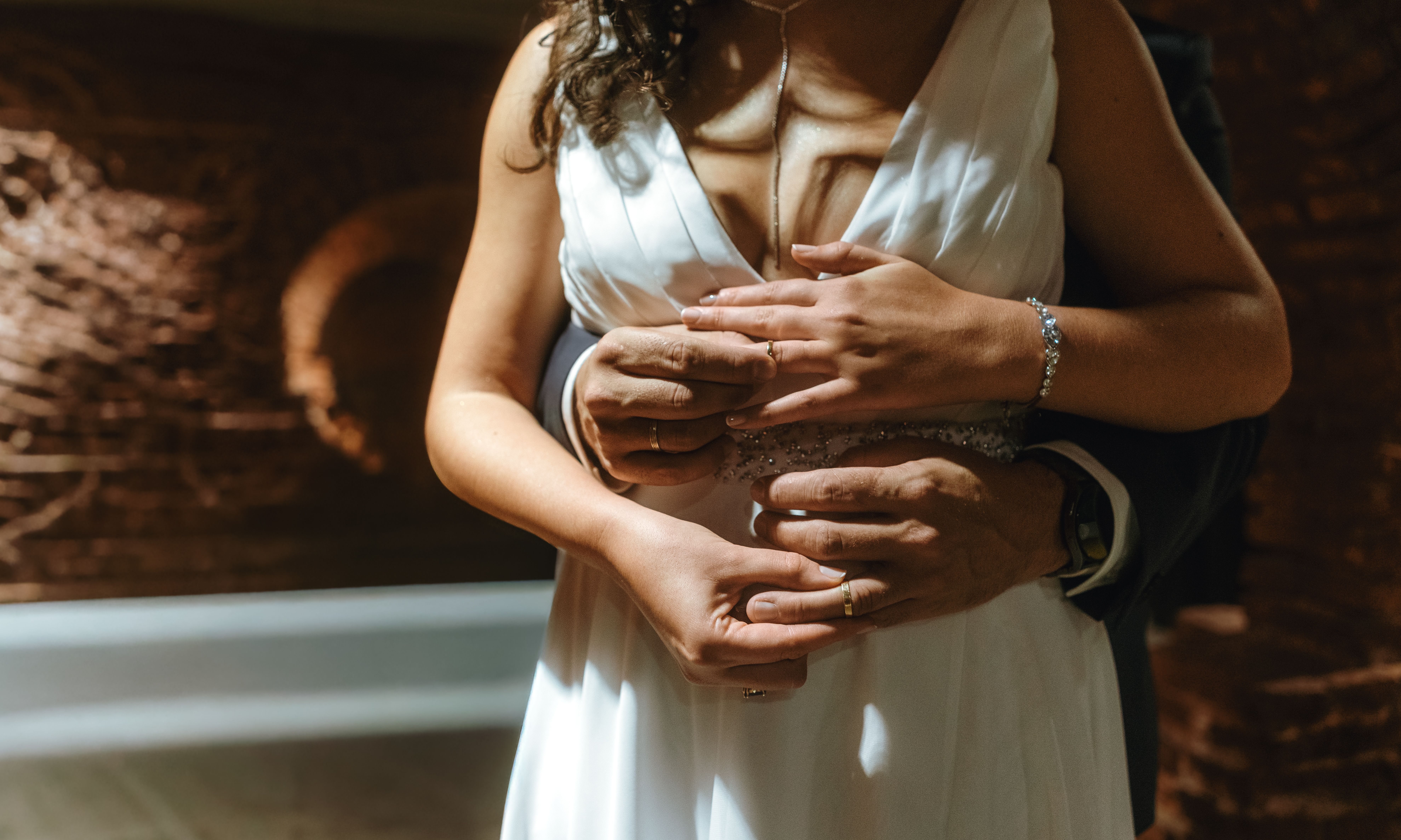 Close-up of a bride and groom's hands embracing, showcasing love and unity.