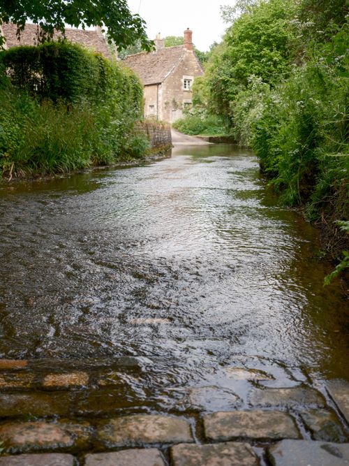 Free Tranquil creekside path with cobblestones and lush greenery in Lacombe, AB, Canada. Stock Photo