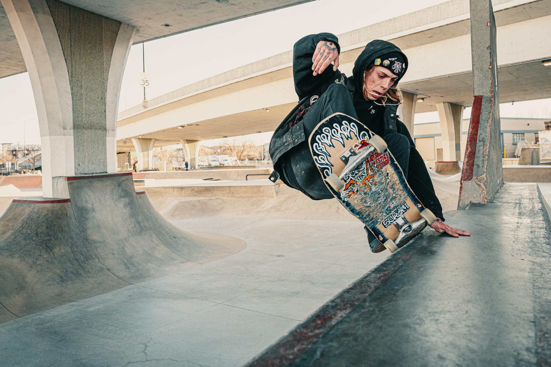 Photo of Man in Black Hoodie Doing a Skateboarding Trick at at Skate Park