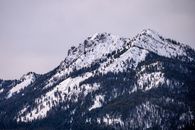 在宁静的冬季，白雪覆盖的雄伟山峰与针叶林构成了一幅美景