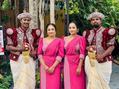 Group portrait of adults in ornate Sri Lankan wedding attire outdoors in Katunayake.