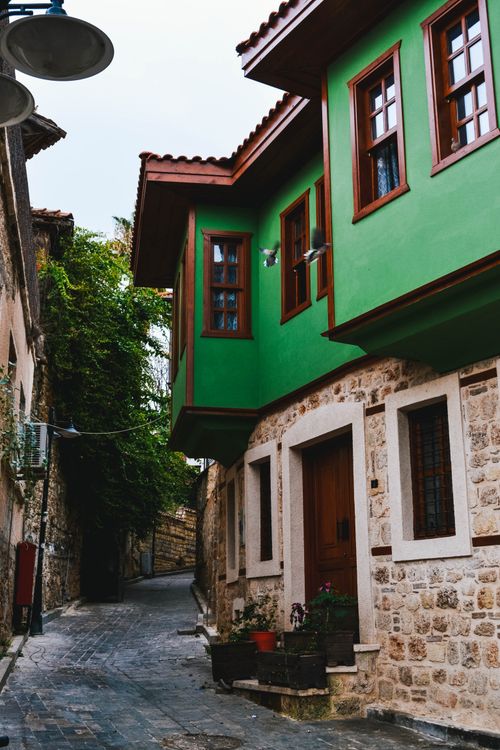 Free Peaceful cobblestone alley with vibrant green house showcasing traditional architecture. Stock Photo