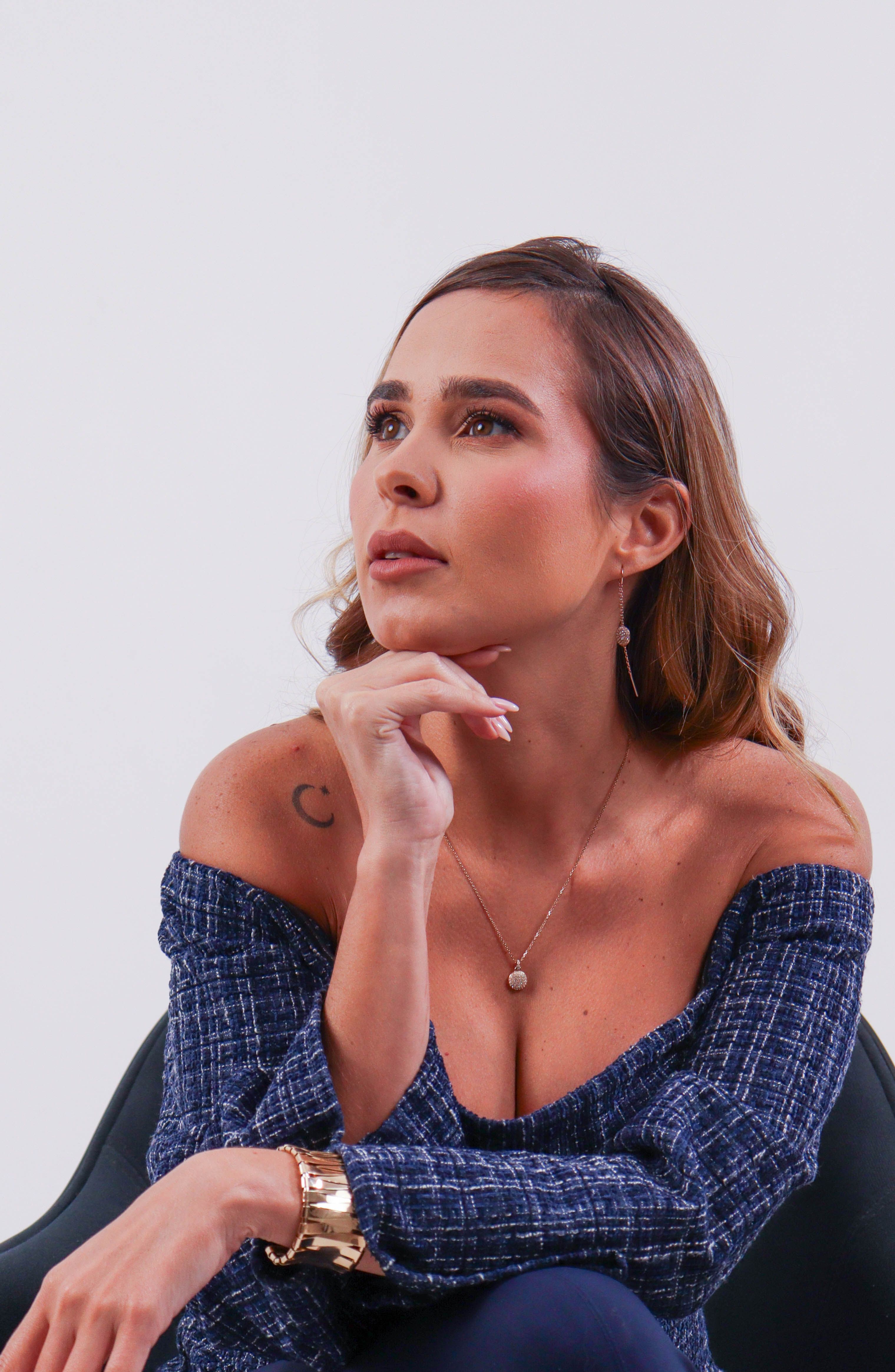 Portrait of a woman in a blue off-shoulder dress with thoughtful expression indoors.