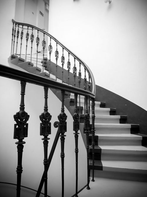 Free Black and white photo of a spiral staircase with ornate railing in Wrocław, Poland. Stock Photo