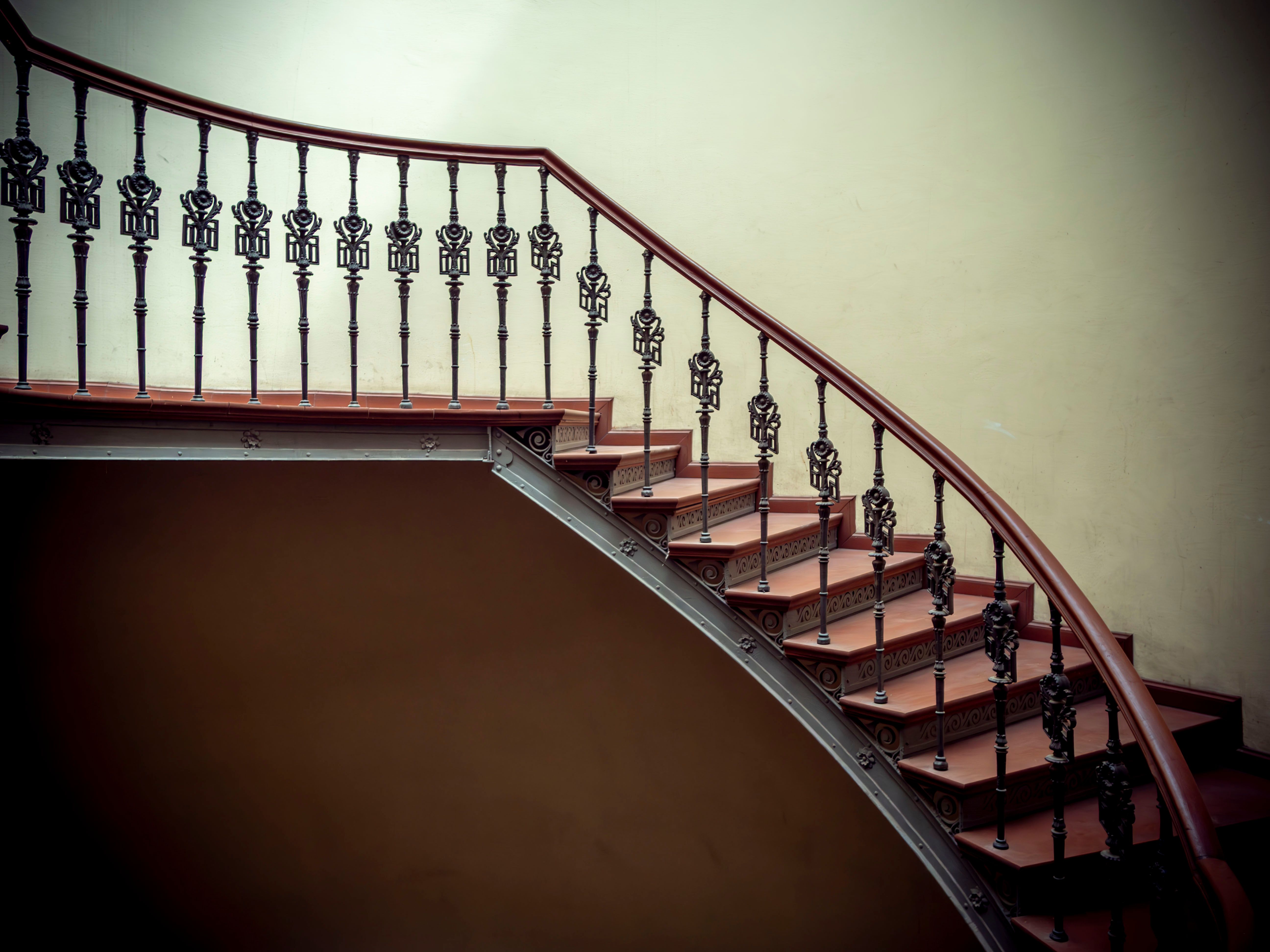 Escalier tournant à balustres de fer forgé et main courante en bois
