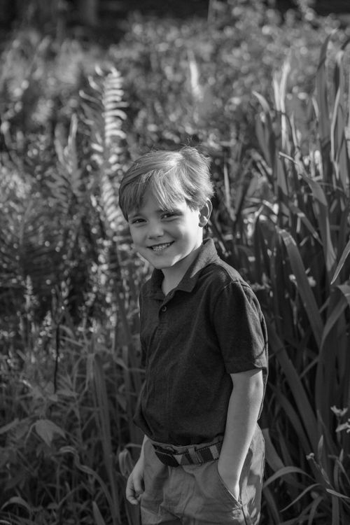 Free A cheerful young boy smiling in a natural setting captured in black and white. Stock Photo