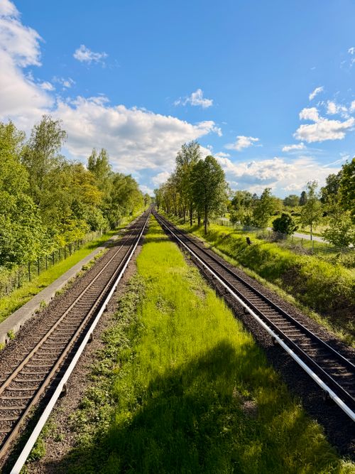 Free Explore scenic railway tracks stretching infinitely through lush greenery under a bright blue sky. Stock Photo
