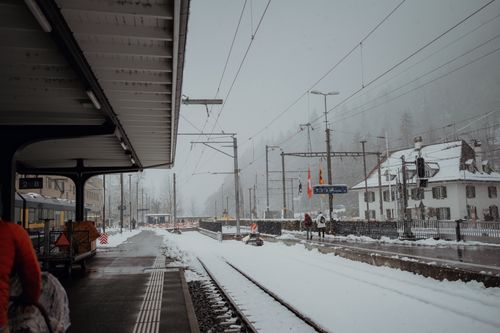 Free A serene winter scene at an Alpine train station with snow-covered tracks and buildings. Stock Photo