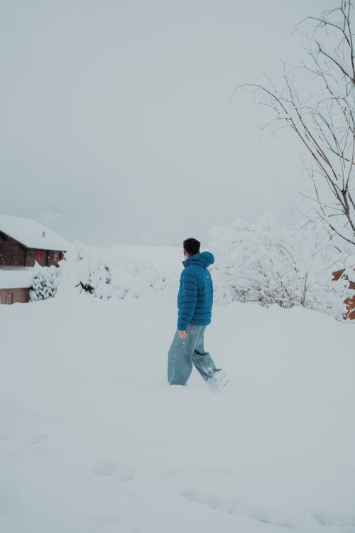 Free A person in a blue jacket walks through deep snow, capturing the essence of winter serenity. Stock Photo