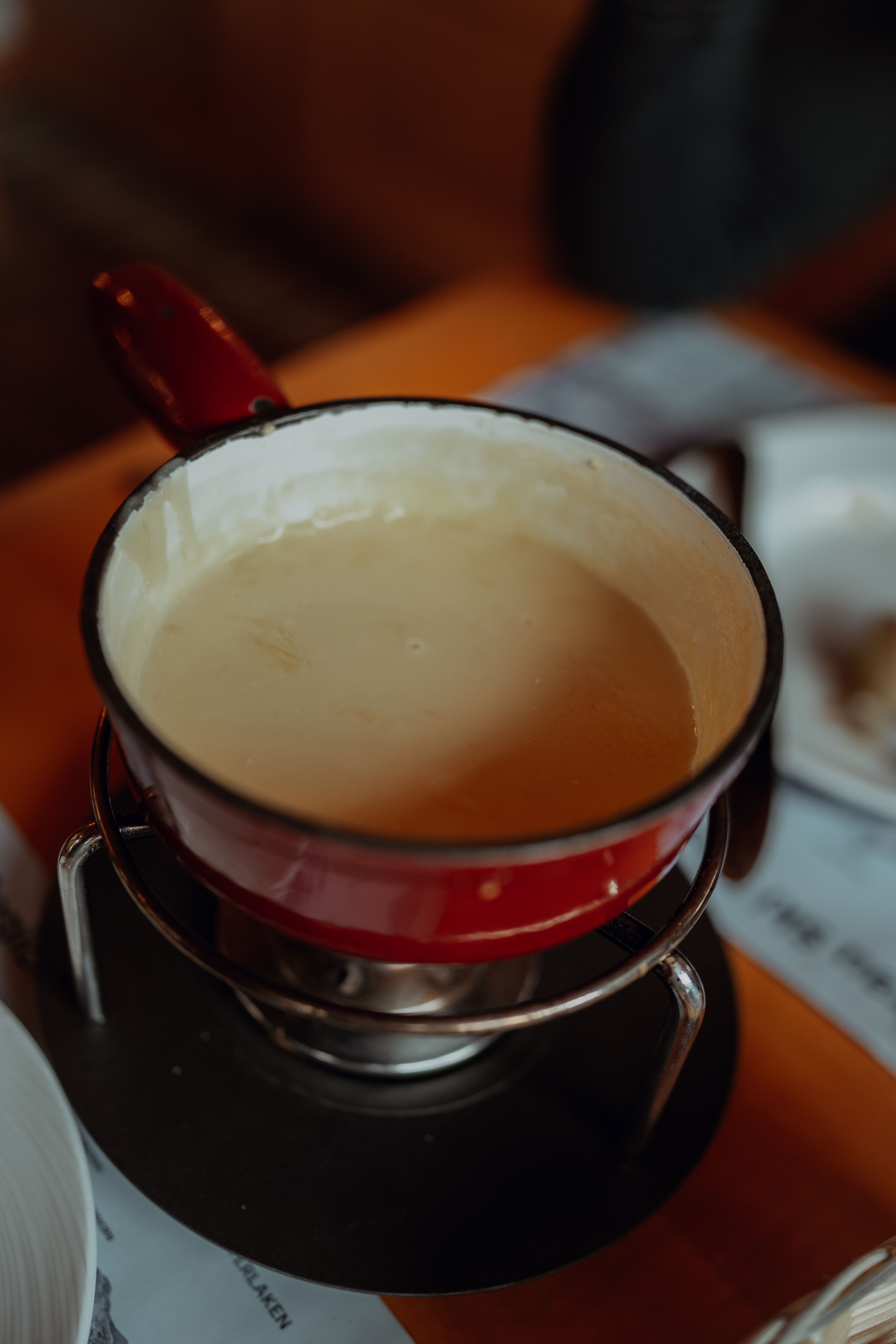 Caquelon rouge de fondue au fromage posé sur son réchaud, vu de haut