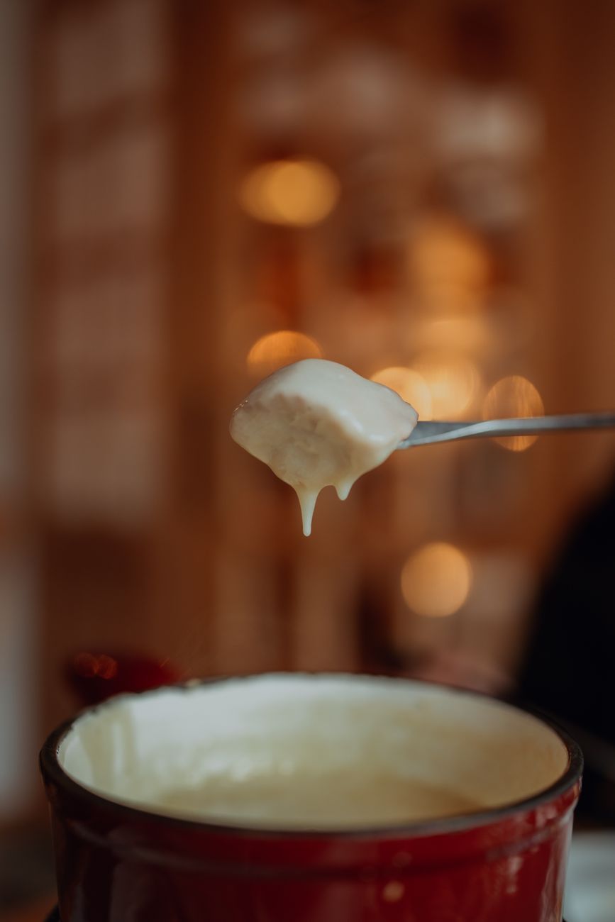 Close-up of a delicious cheese fondue with bread cube dipped in creamy cheese.